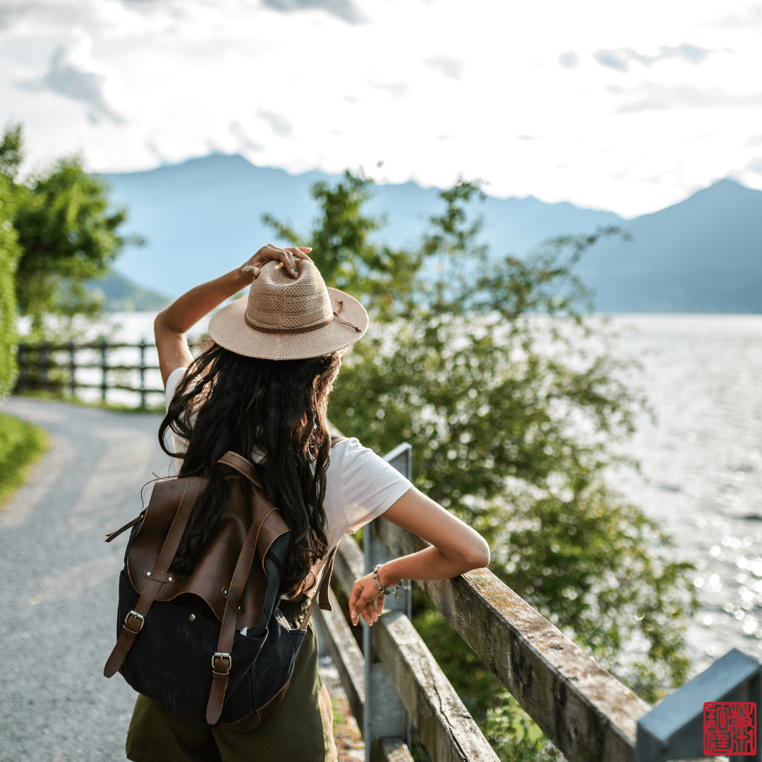 A Photo of a back of a person with a tourist outfit looking at the mountains