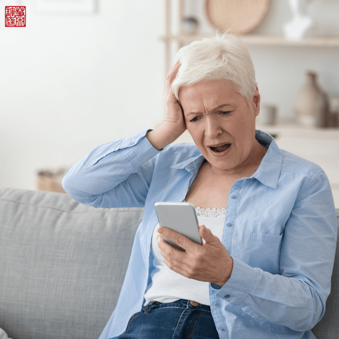 Elderly woman holding her phone in shock