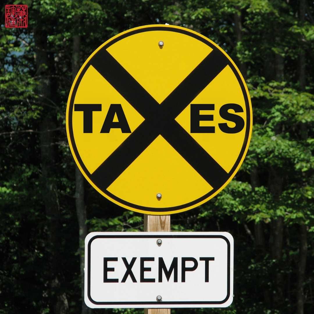 A circular sign that has the word taxes crossed-out and below has another sign that says exempt which represents Tax exemption