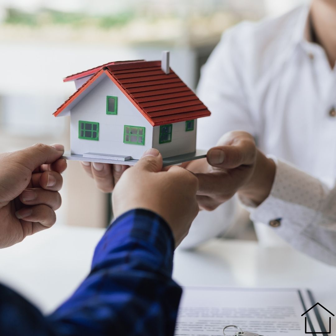 Image of a person holding a miniature house passing it to another person representing Inheritance